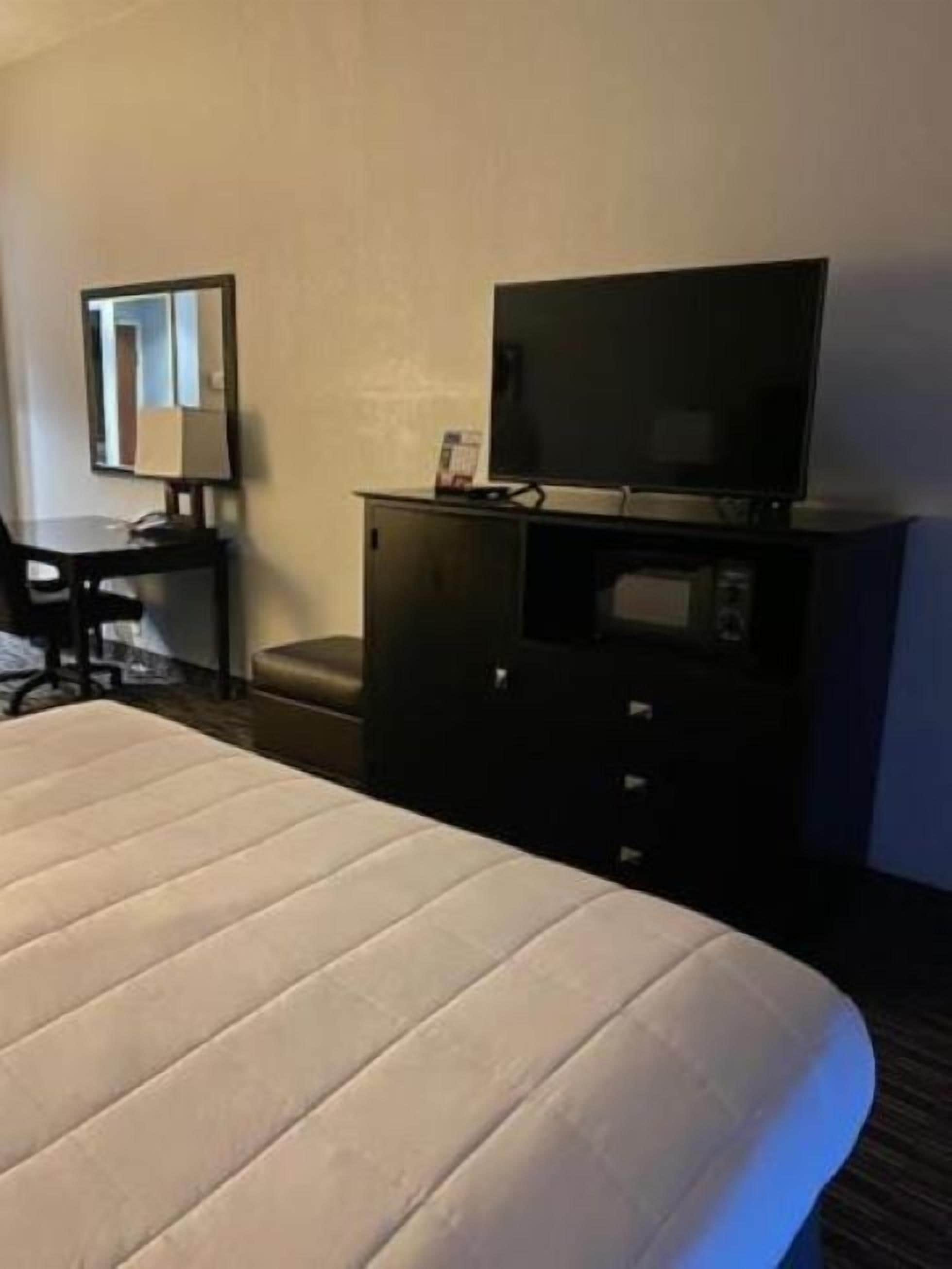 Una habitación de hotel con cama, escritorio, televisión y minibar.