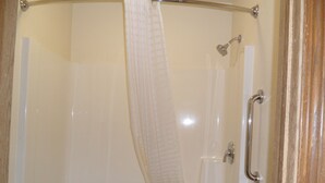 A glass-enclosed shower with a shower curtain, a handheld showerhead, and a handheld faucet. - Der Ruhe Blatz Motel (Shipshewana)