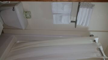 A bathroom with a bathtub, a toilet, and a towel rack with towels.