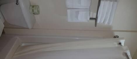 A bathroom with a bathtub, a toilet, and a towel rack with towels.