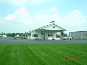 A motel with a white exterior, a covered front porch, and a horse-drawn carriage decoration. - Der Ruhe Blatz Motel (Shipshewana)