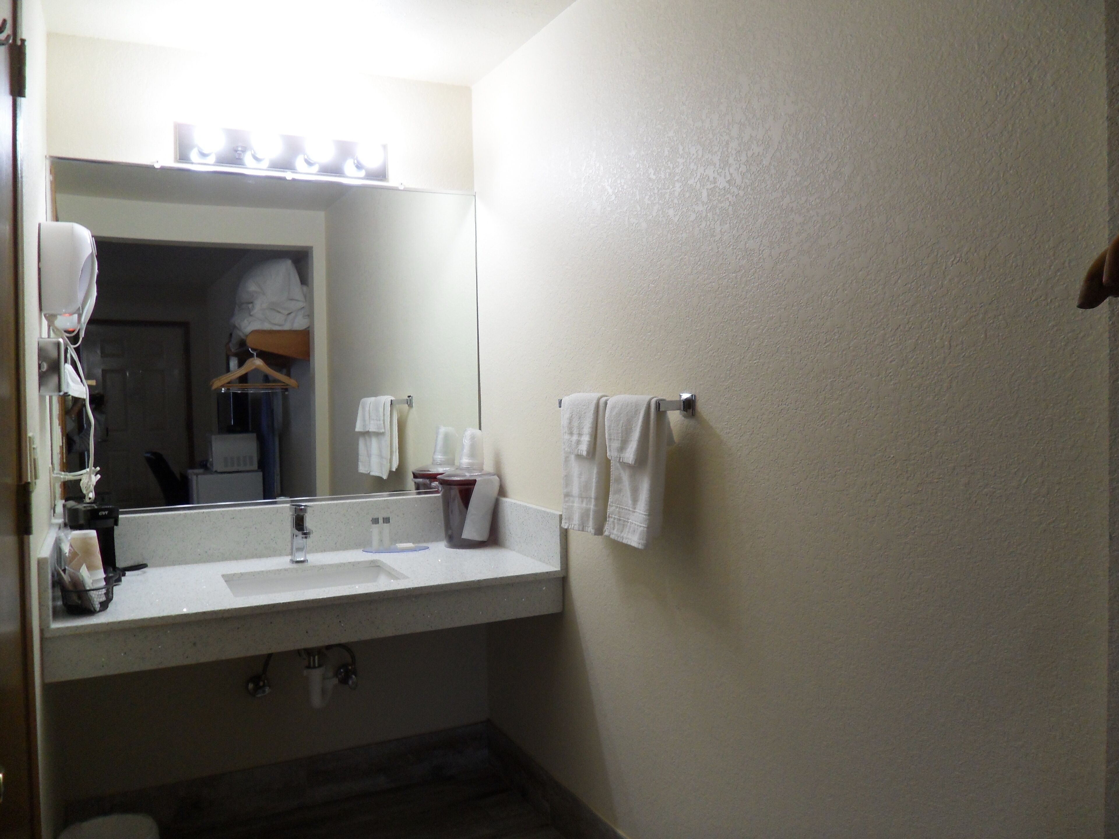 A bathroom with a sink, mirror, and towel rack.