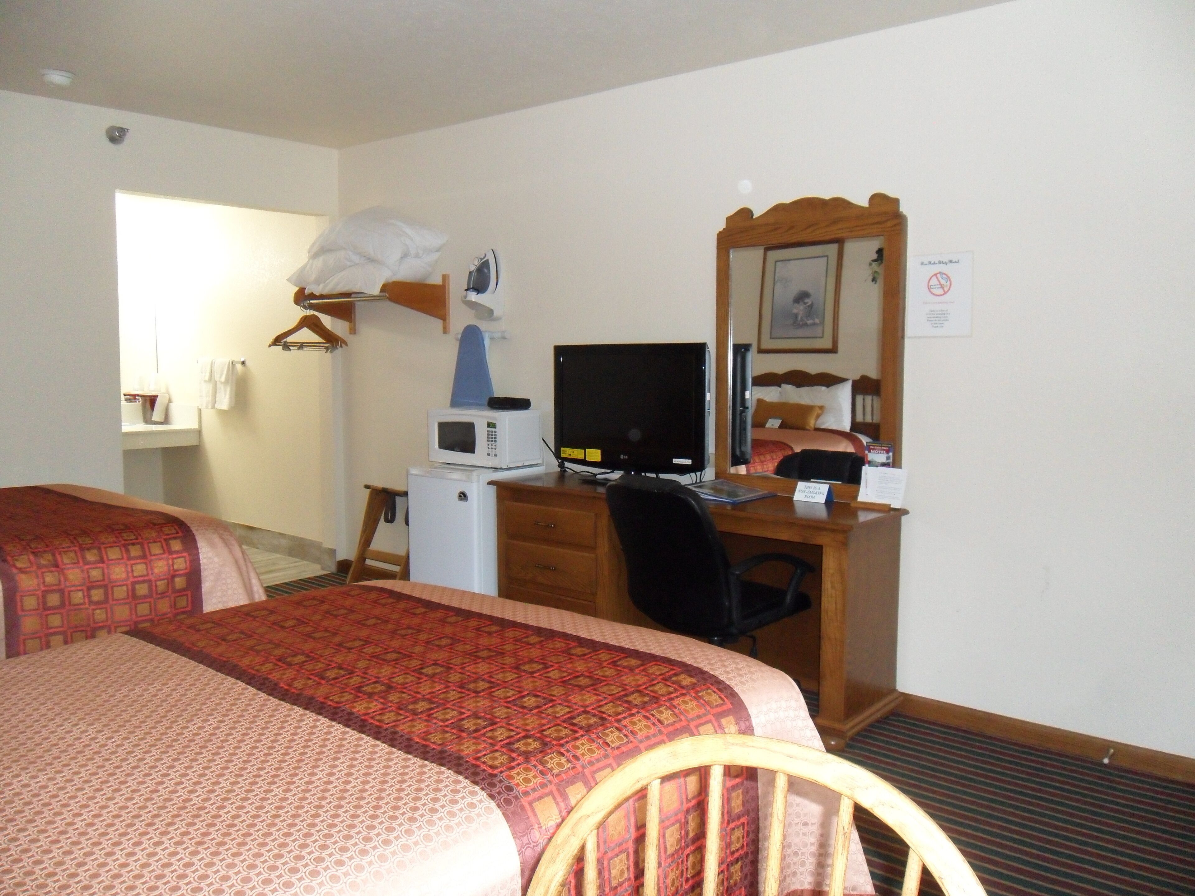 A hotel room with two beds, a desk with a computer, a microwave, and a small refrigerator.