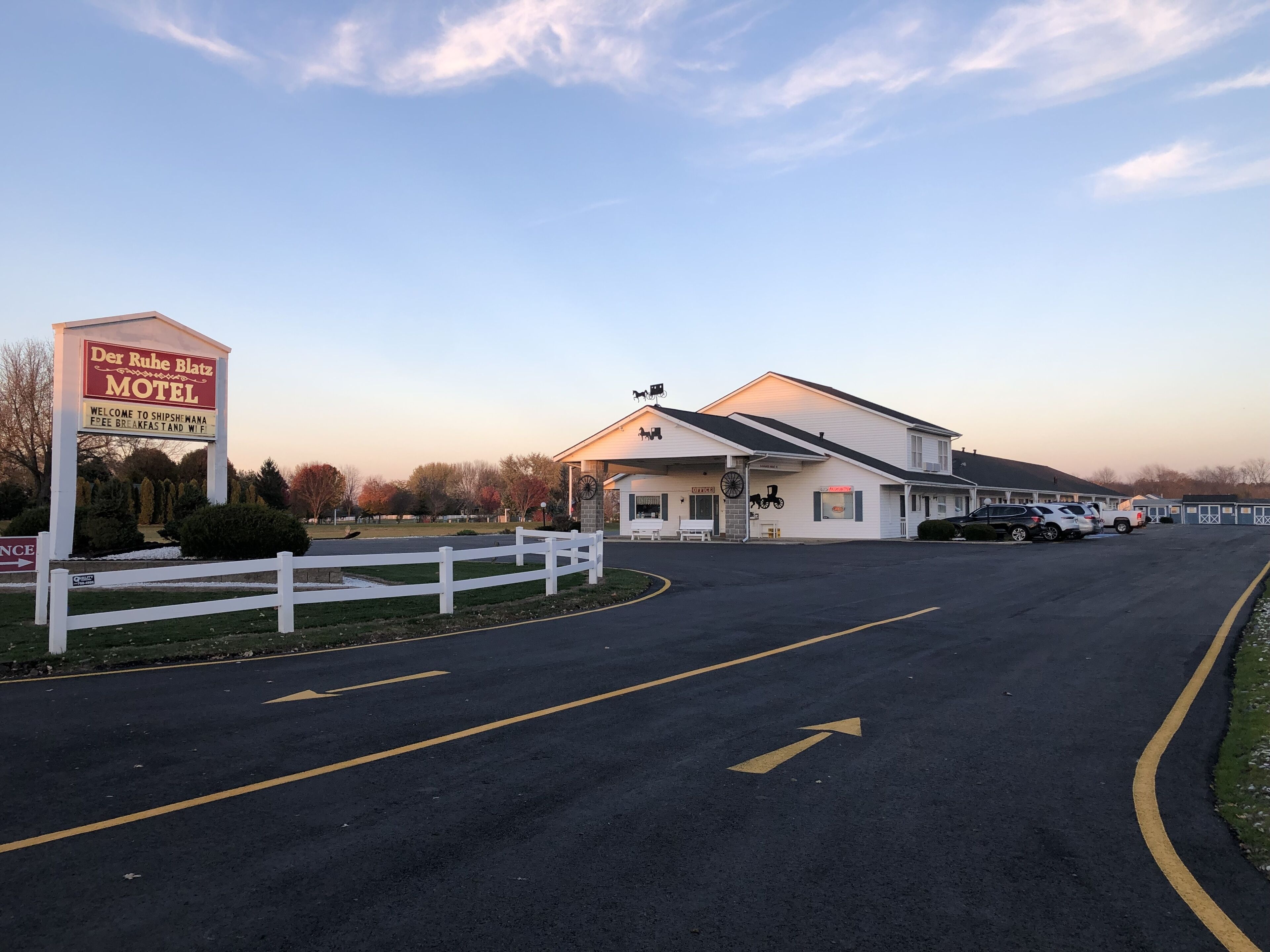 A motel with a signboard, a parking lot, and a building with a white facade.