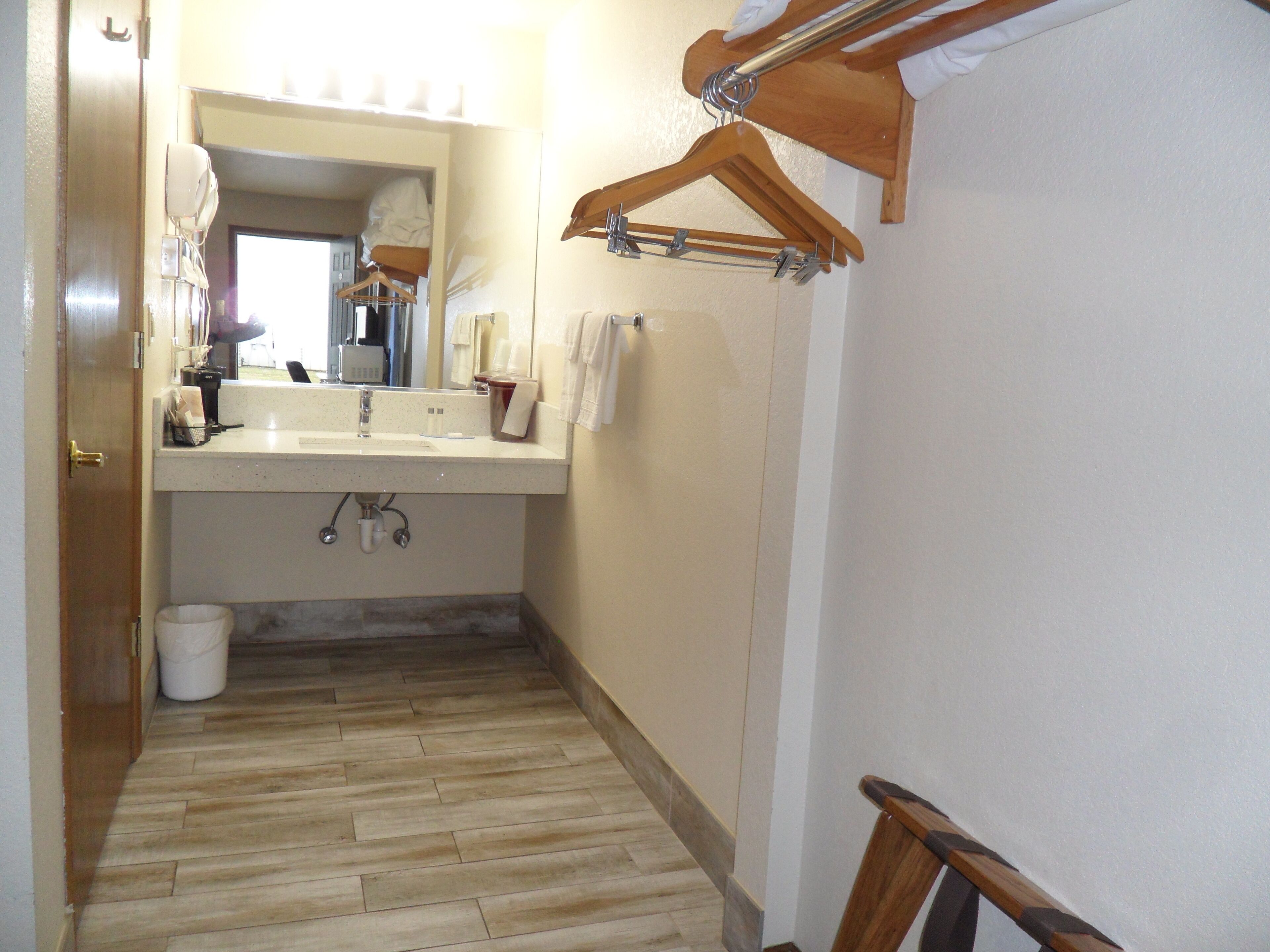 Une petite salle de bain comprenant un lavabo, un miroir et un porte-serviettes en bois.