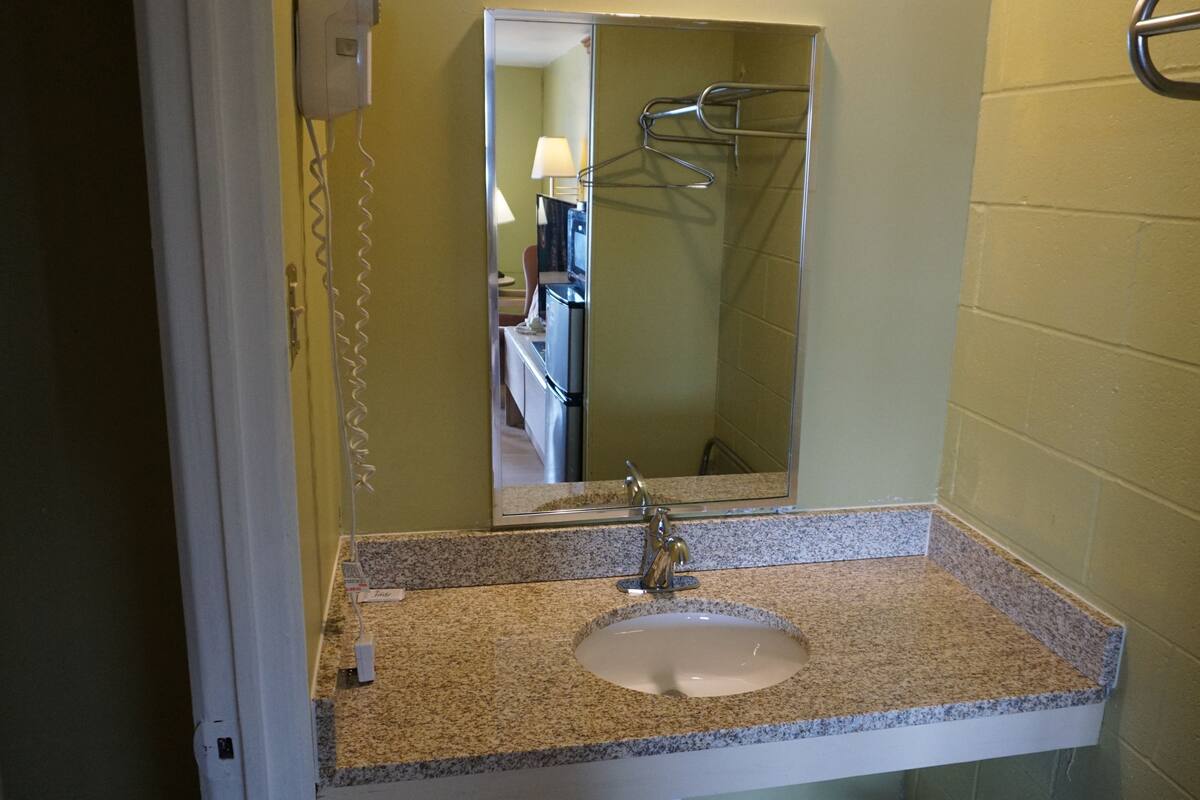 A bathroom with a granite countertop sink, a mirror, and a towel rack.
