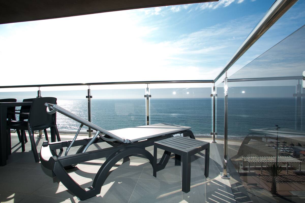 Un balcon avec vue sur l’océan, un tapis de course et un espace salon extérieur.