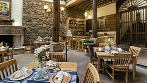 A restaurant with stone walls, wooden beams, and tables set for dining. - Hotel Casa del Naranjo (Patzcuaro)