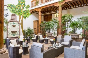 An outdoor patio with wicker furniture, potted plants, and a wooden pergola. - Hotel Casa del Naranjo (Patzcuaro)