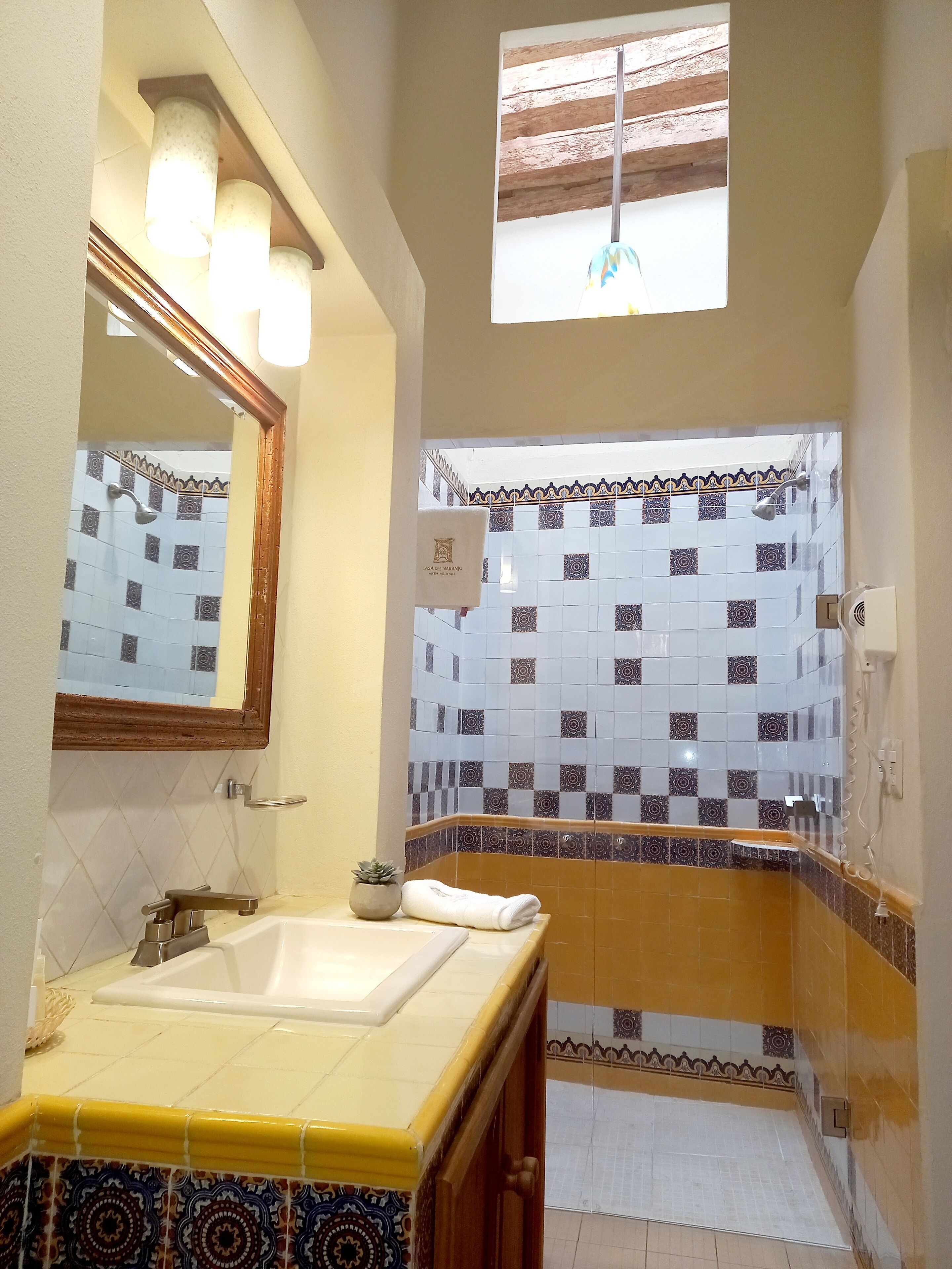 Un baño con lavamanos, espejo y zona de ducha.