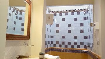 Un baño con lavamanos, espejo y zona de ducha.