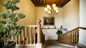 A staircase with wooden balusters, a potted tree, and a chandelier. - Hotel Casa del Naranjo (Patzcuaro)