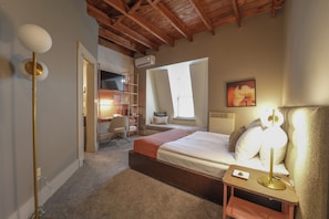 Una habitación de hotel con cama, mesita de noche, lámpara y escritorio con silla.