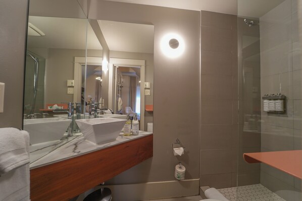 A modern bathroom with a large mirror, a white sink, and a glass-enclosed shower.