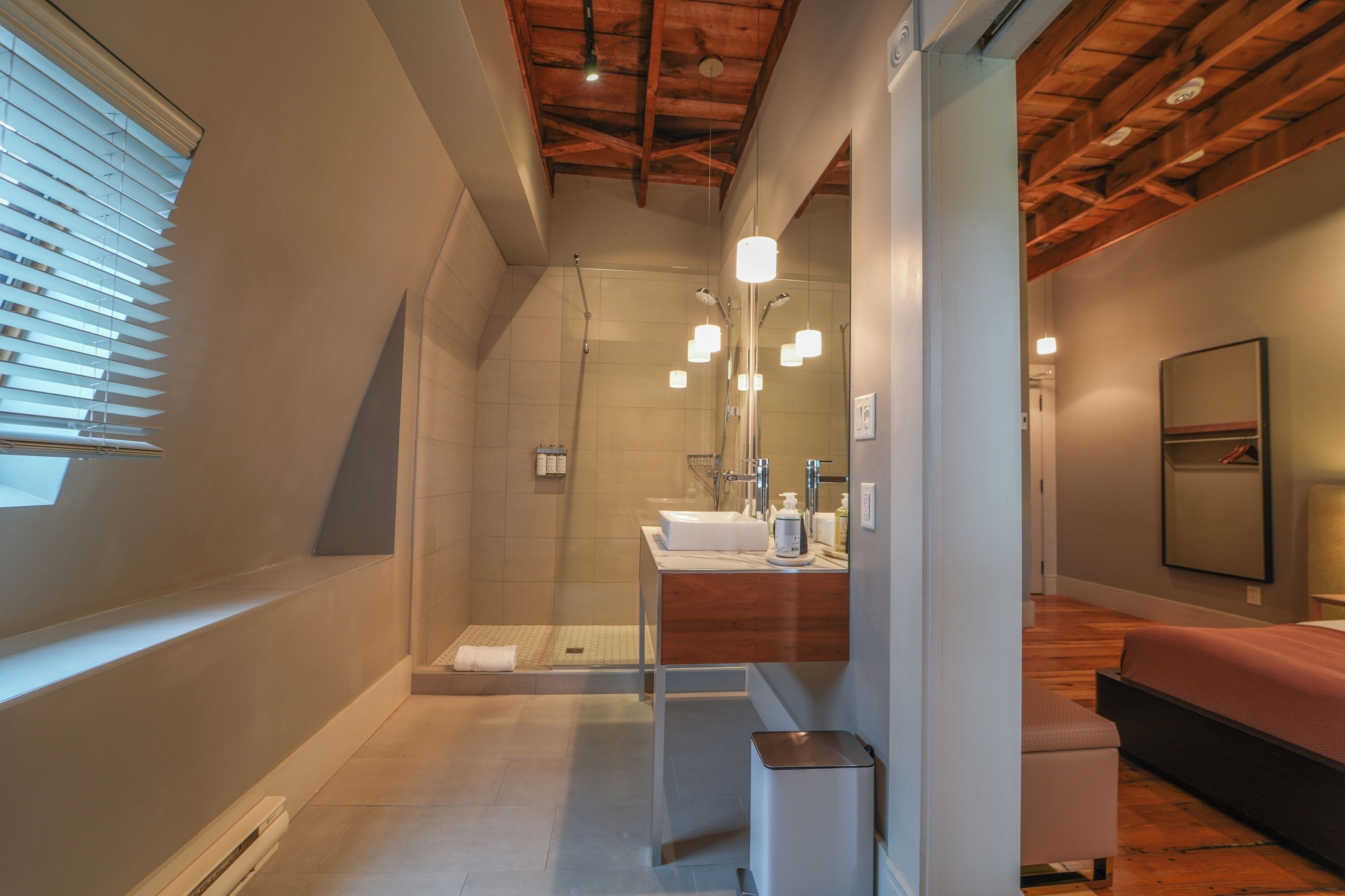 A modern bathroom with a glass shower enclosure, a wooden vanity, and a large mirror.
