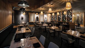 Un restaurante con paneles de madera, varias mesas de comedor e iluminación colgante.
