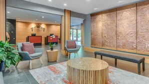 Un moderno vestíbulo de hotel con mostrador de recepción, zona de estar y paneles decorativos en la pared.