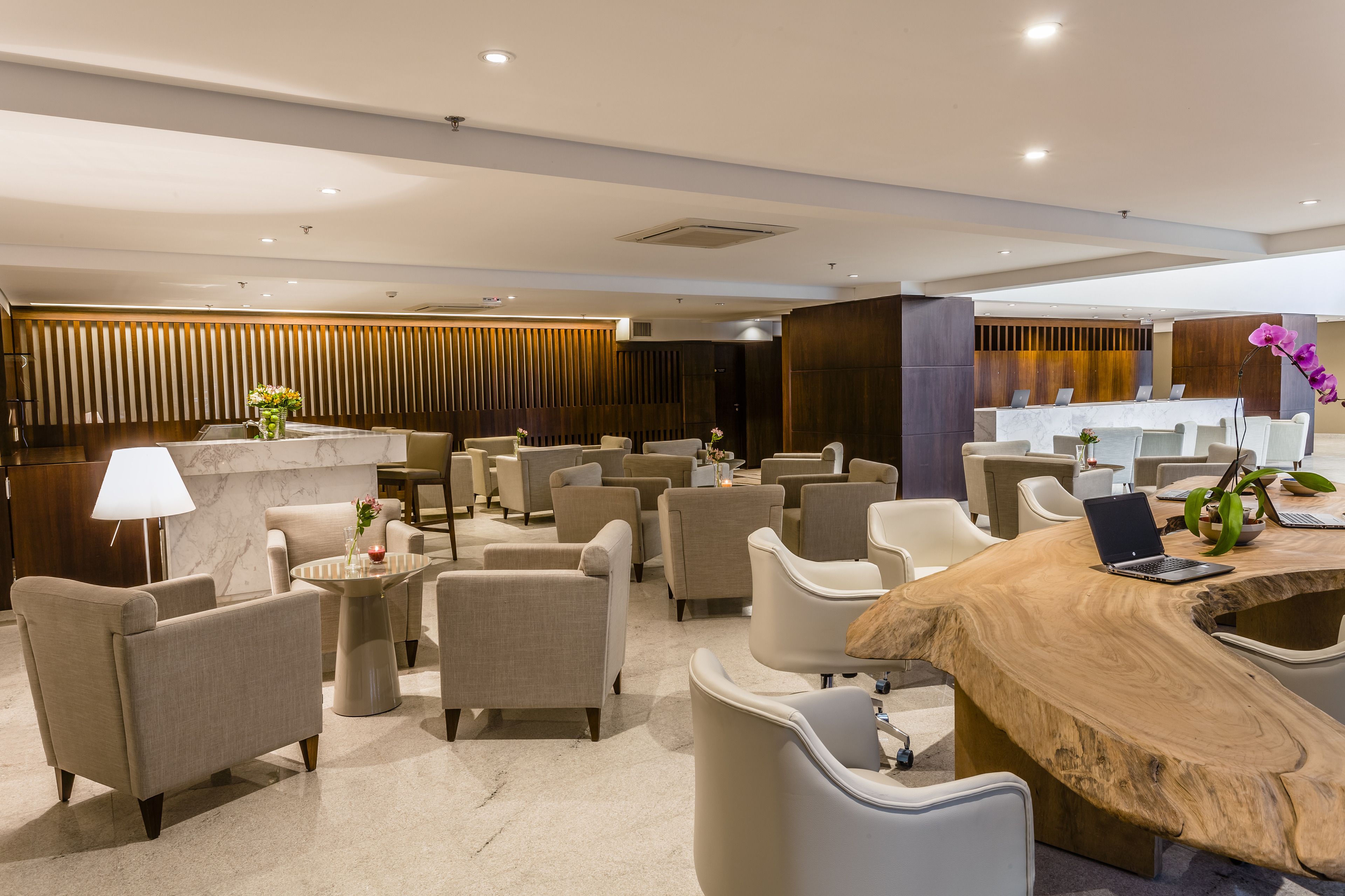 A modern lounge area with multiple seating options, a reception desk, and a wooden coffee table with a laptop.
