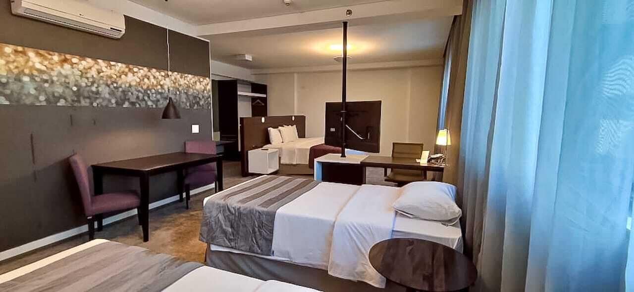 Ein Hotelzimmer mit zwei Betten, einem Schreibtisch, einem Stuhl, einem kleinen Tisch und einem Fernseher.