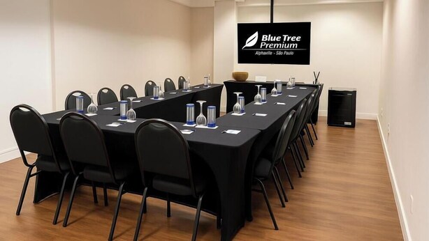 A conference room with a long table, black chairs, and a flat-screen TV displaying "Blue Tree Premium".