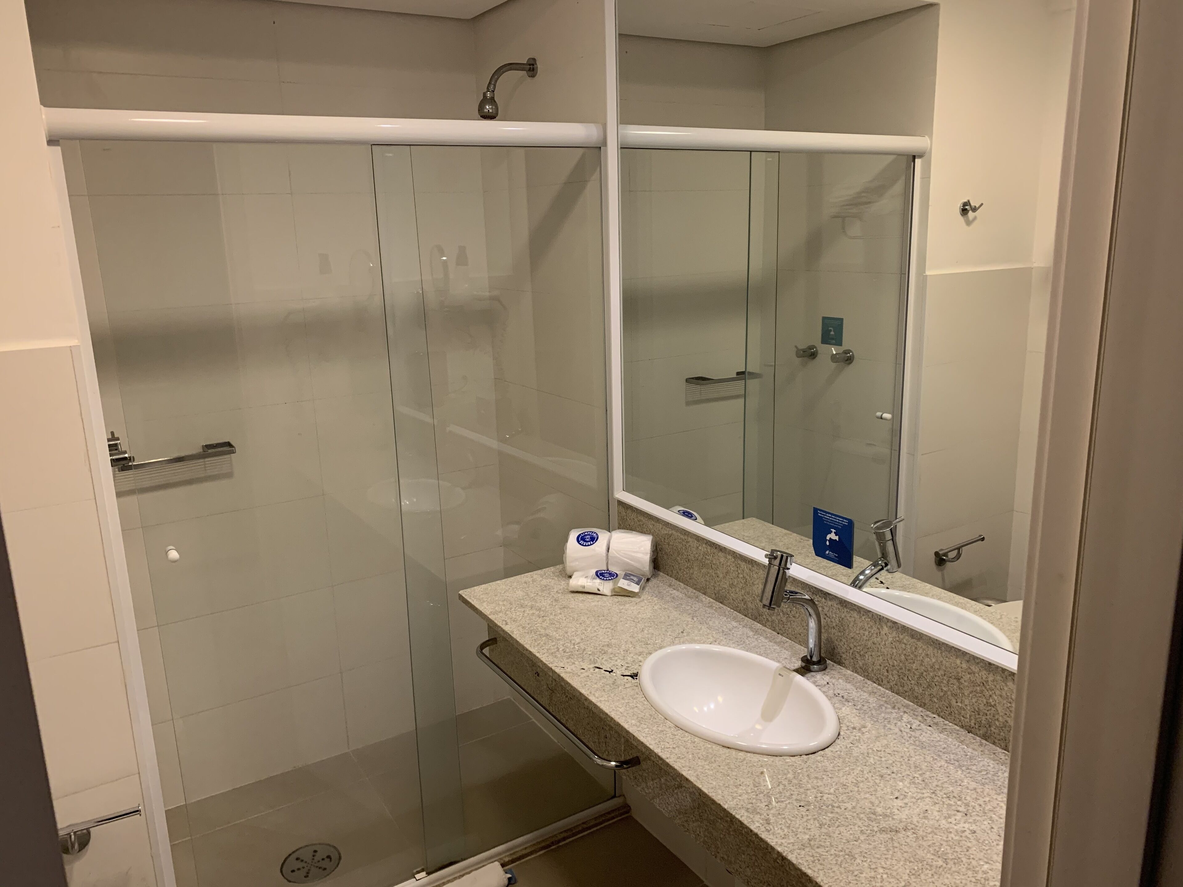 Une salle de bain avec une douche à parois de verre, un lavabo avec un miroir et un distributeur de serviettes.