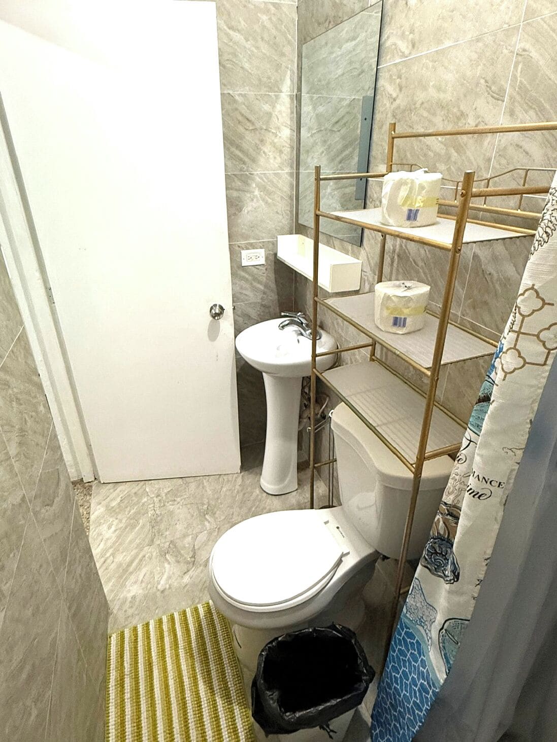 A bathroom with a toilet, bidet, and a shelf with toiletries.
