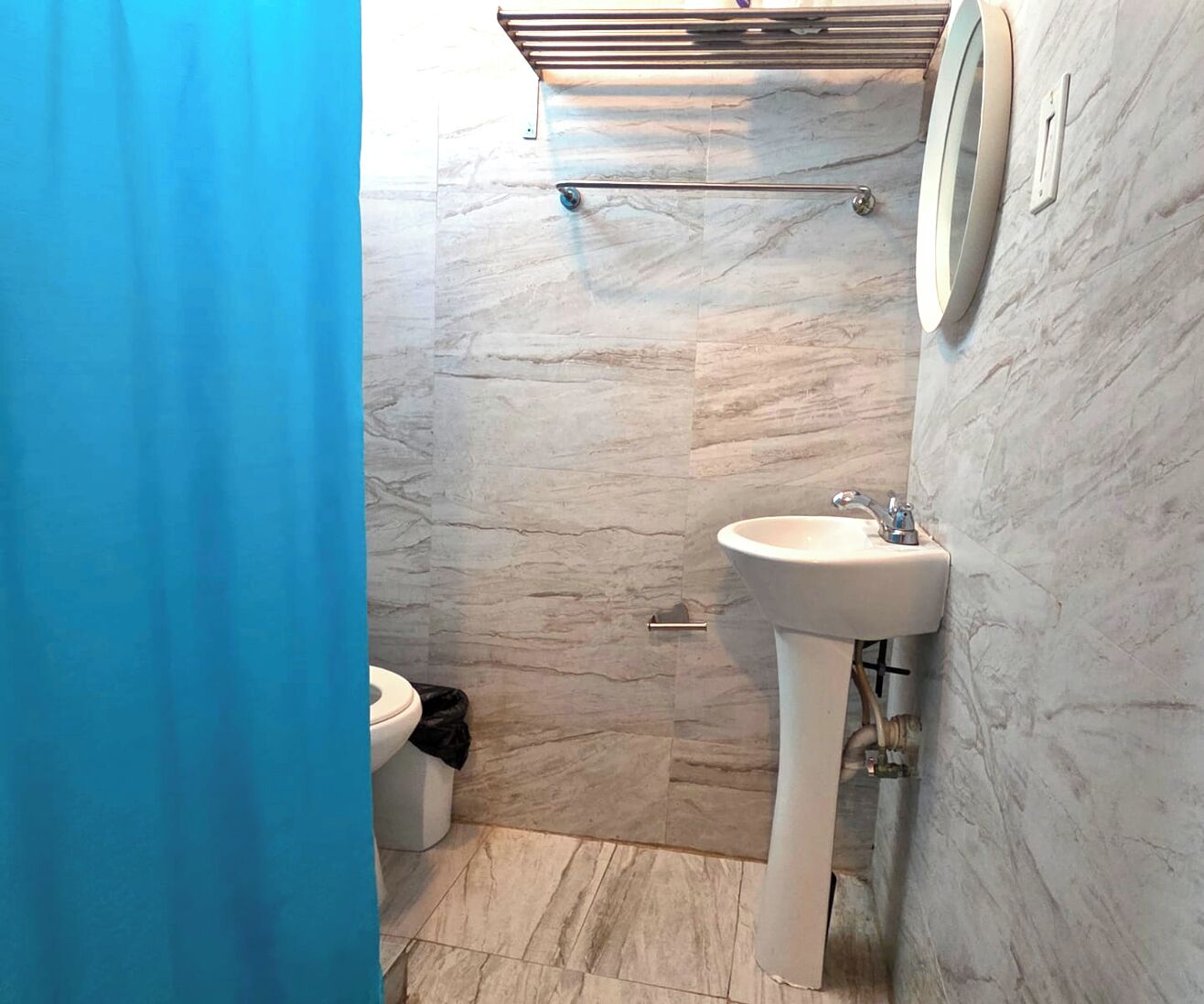 A bathroom with a marble floor, a white sink, and a toilet.