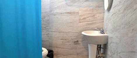 A bathroom with a marble floor, a white sink, and a toilet.