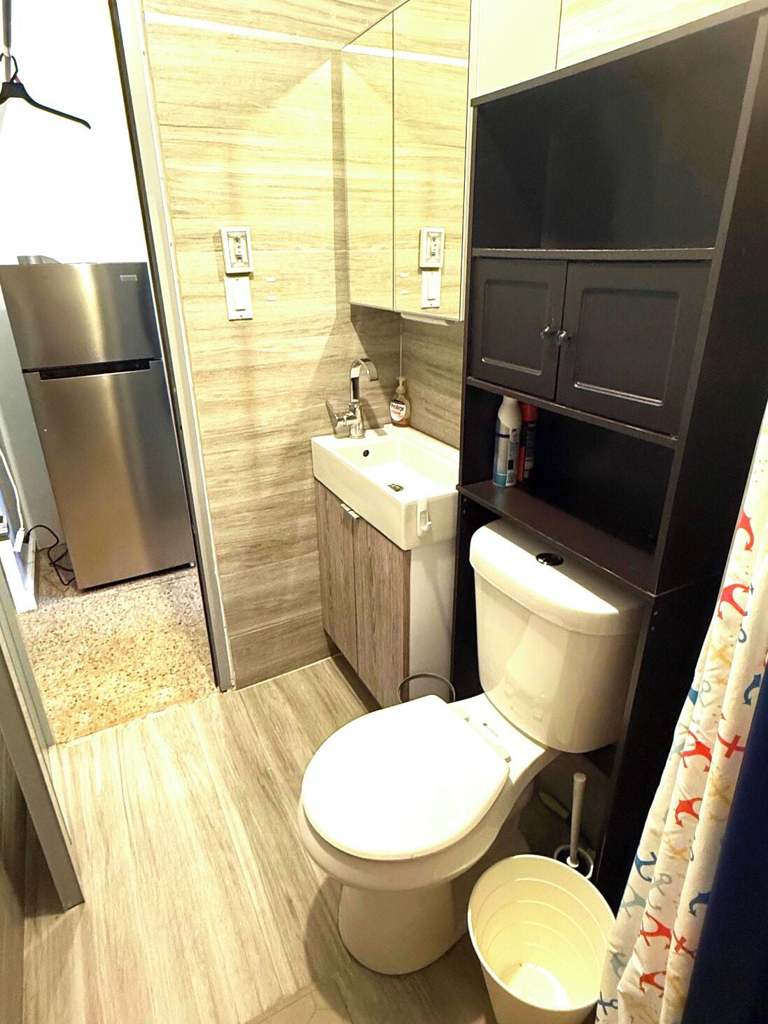 Un bagno compatto con un WC, un lavandino e un piccolo mobiletto sopra il lavandino.