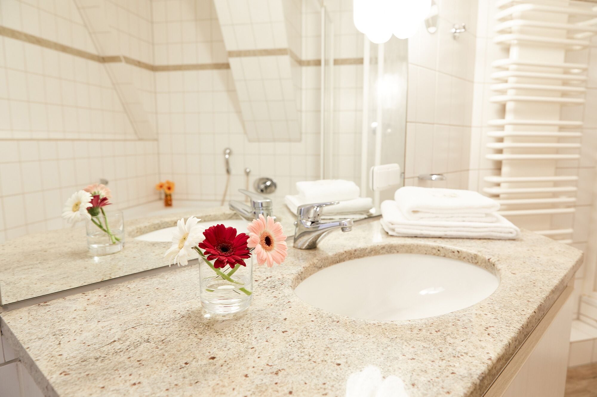 A bathroom with a sink, mirror, and towels.