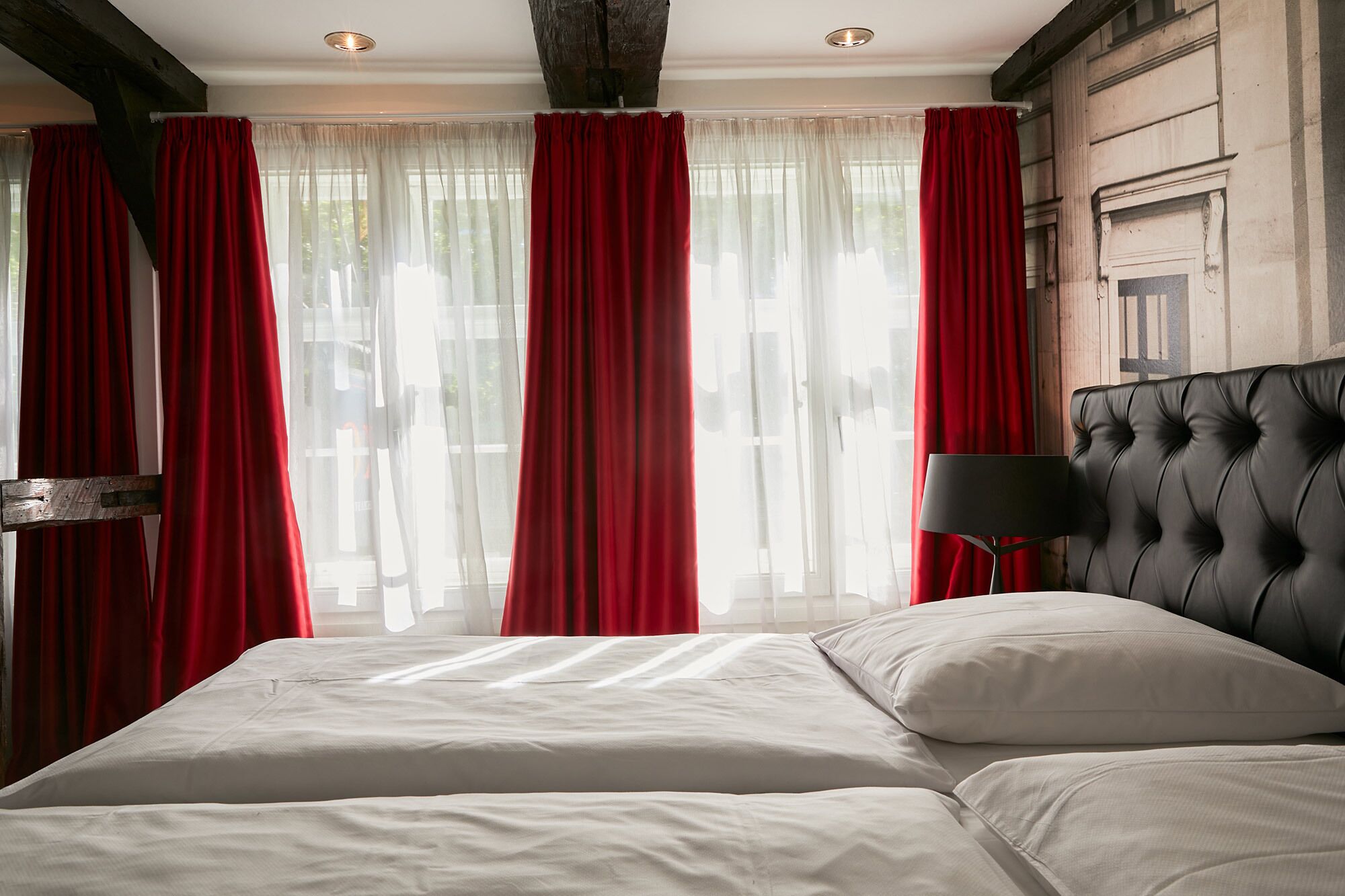 Una camera da letto con un letto grande, tende rosse e una testiera nera.