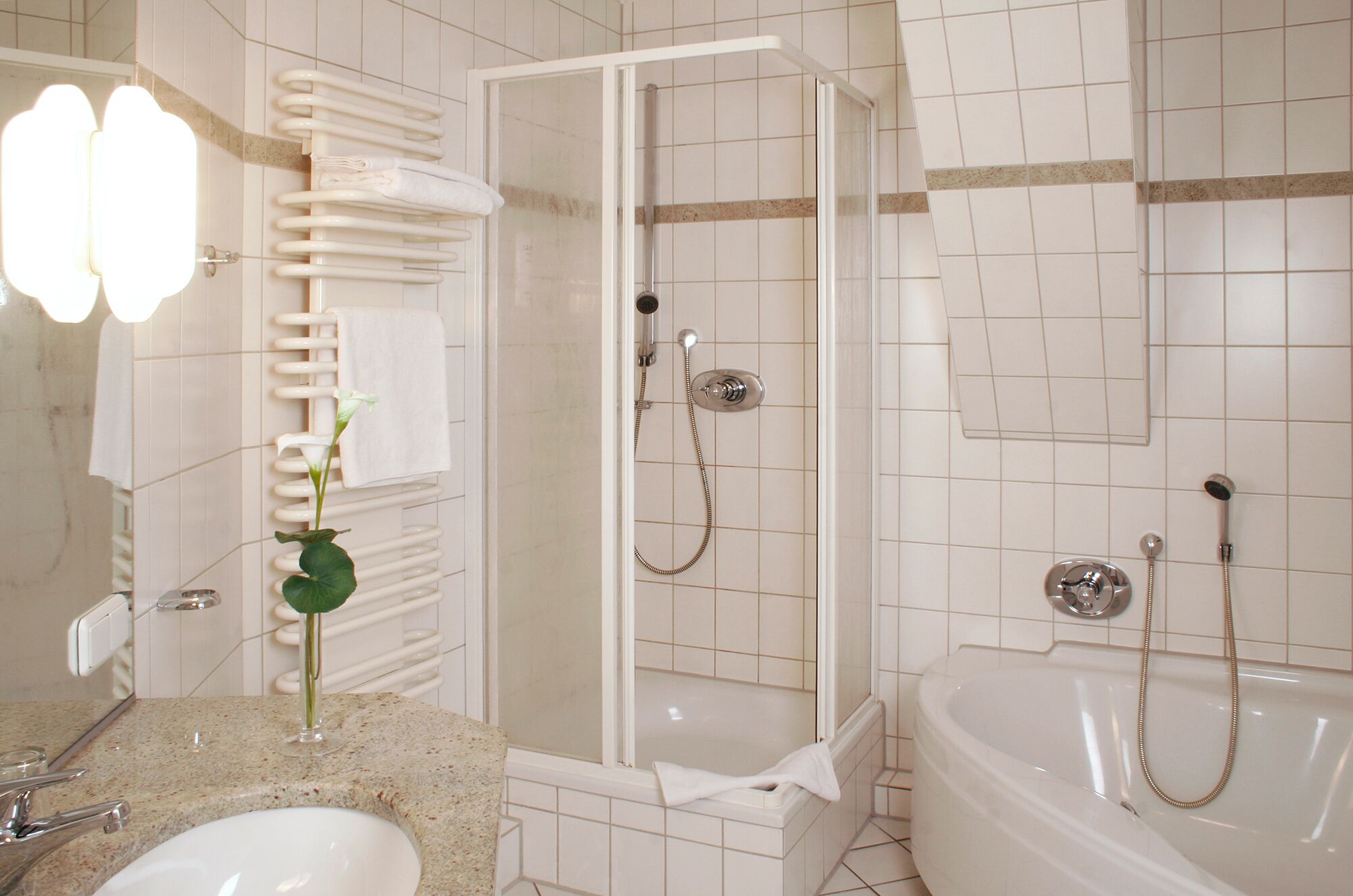 A bathroom with a sink, mirror, towel rack, shower, and bathtub.
