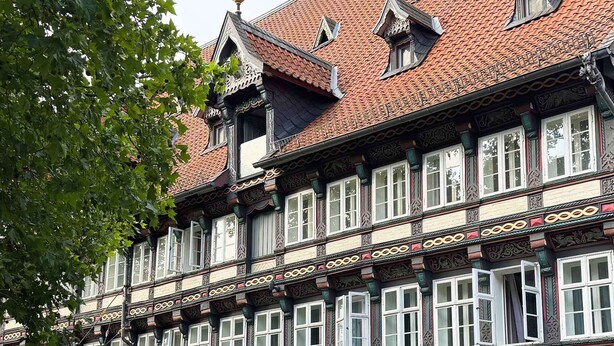 Ein historisches Gebäude mit aufwendigen architektonischen Verzierungen, darunter ein Ziegeldach und dekorative Fensterrahmen.