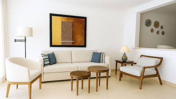 Un salon comprenant un canapé, deux fauteuils, une table basse, un lampadaire et une œuvre d’art accrochée au mur.