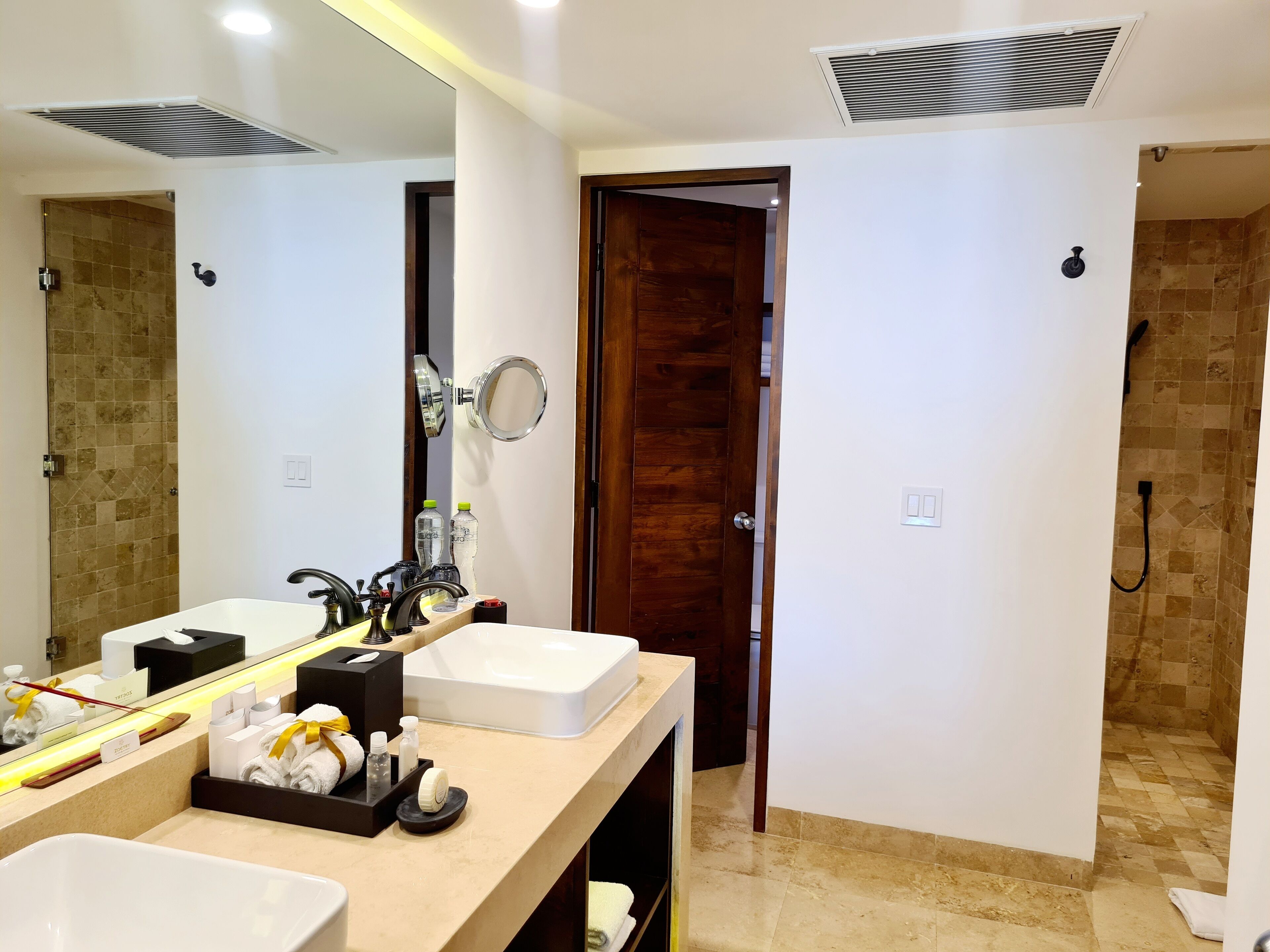 Une salle de bain moderne avec deux lavabos, un grand miroir et un espace douche.