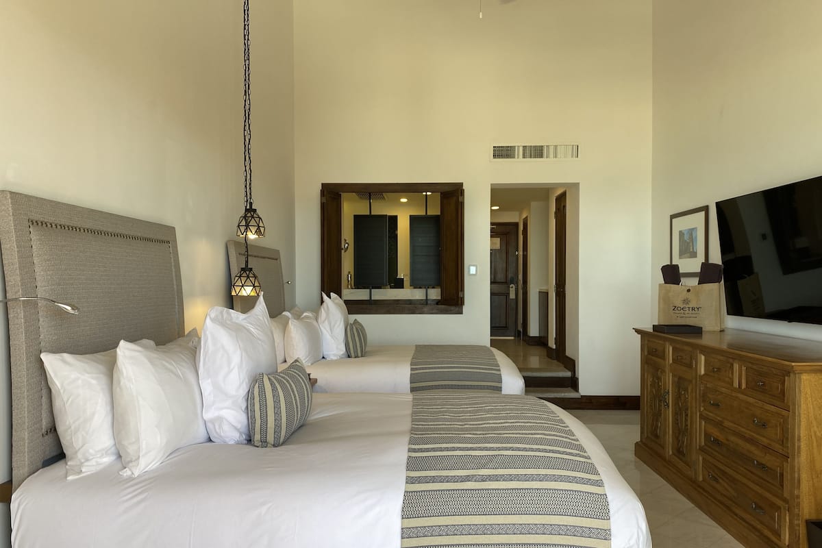 A hotel room with a large bed, a wooden dresser, a television, and a mirror.