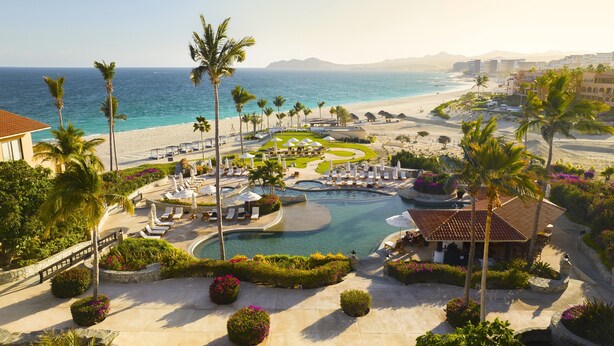 Un resort con piscina, palmeras y vista al mar.