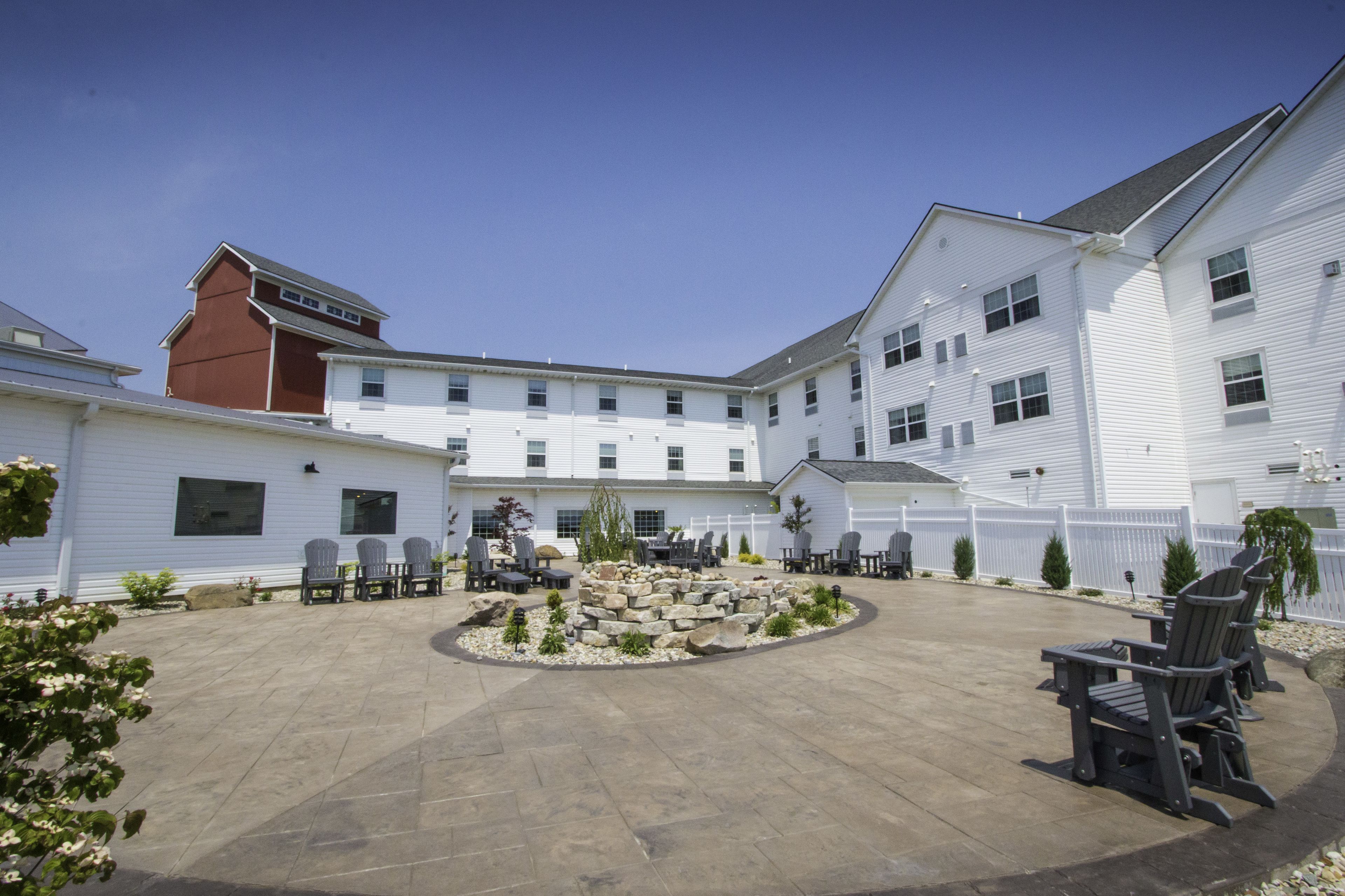 A courtyard with outdoor seating, stone features, and white buildings.