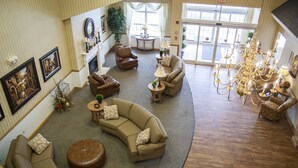 A spacious living area with a curved sectional sofa, a leather ottoman, and a chandelier.