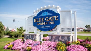 Skilt for Blue Gate Garden Inn med en stenbase og blomsterbede foran.