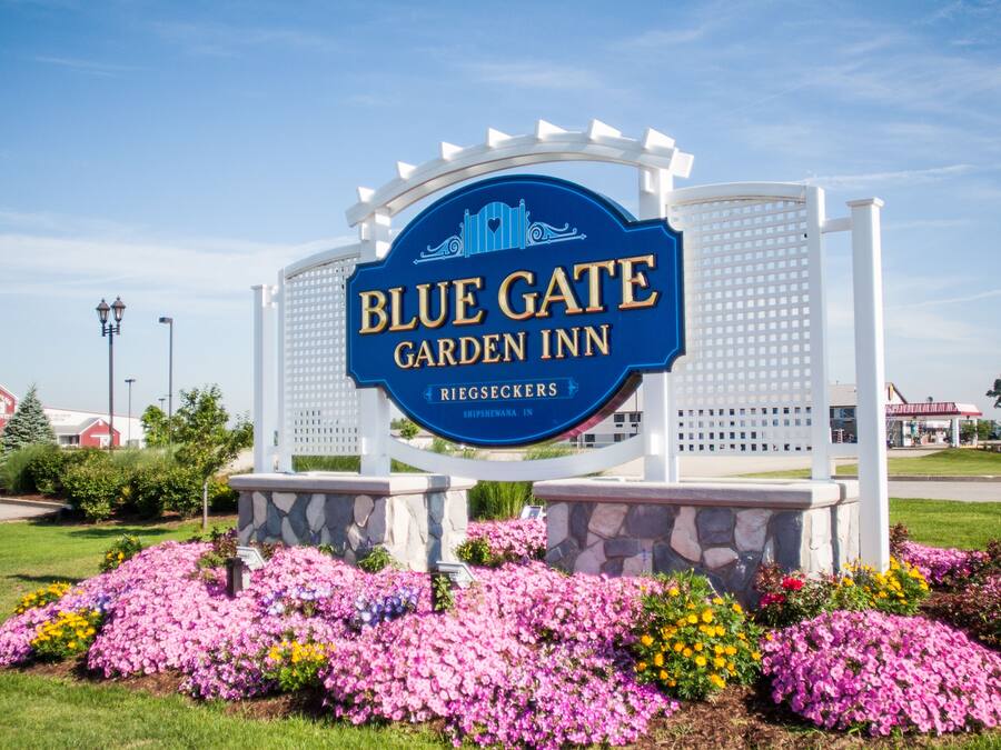 Skilt for Blue Gate Garden Inn med en stenbase og blomsterbede foran.