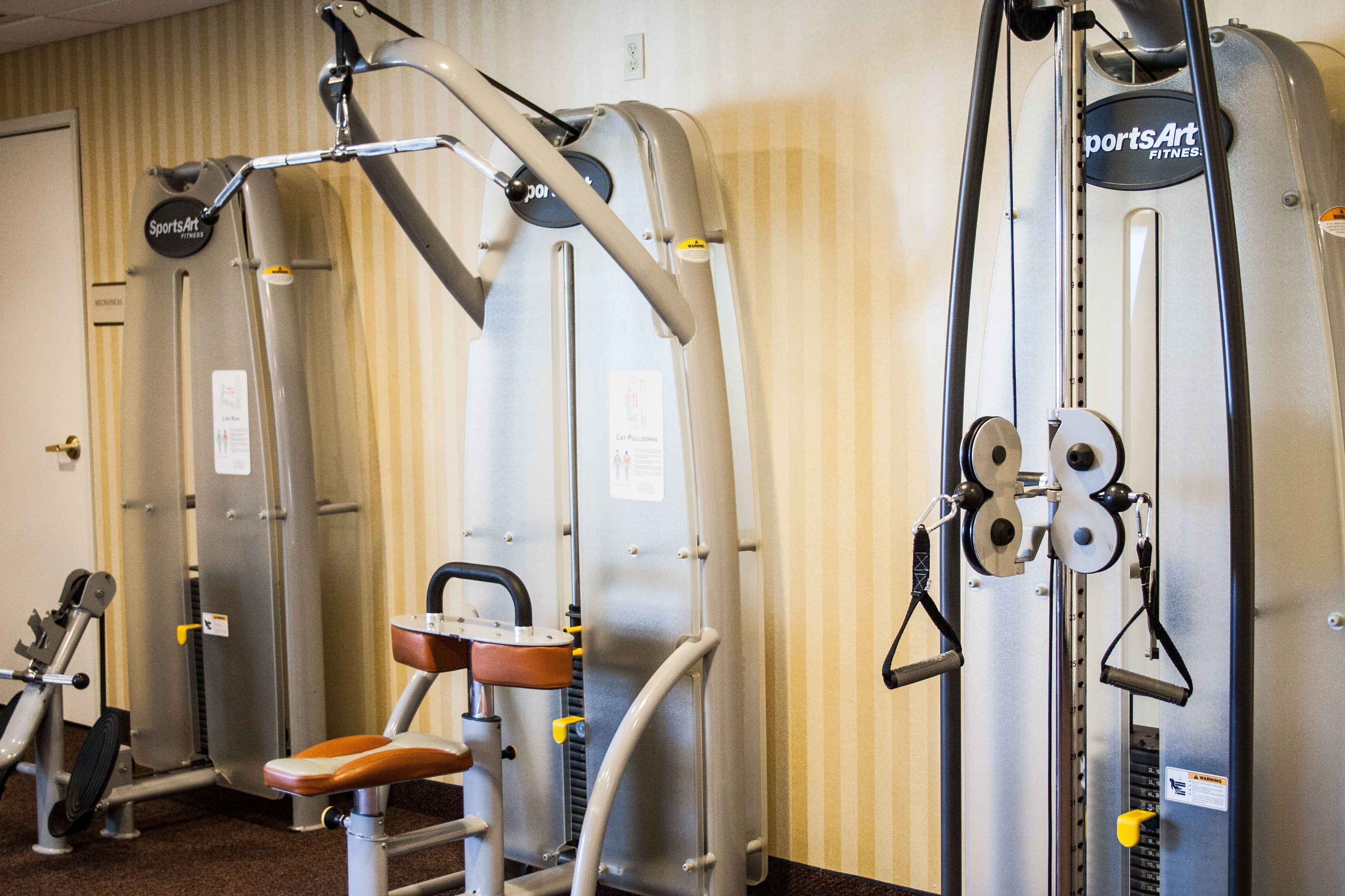 A gym with various exercise machines, including a leg press and a chest press.