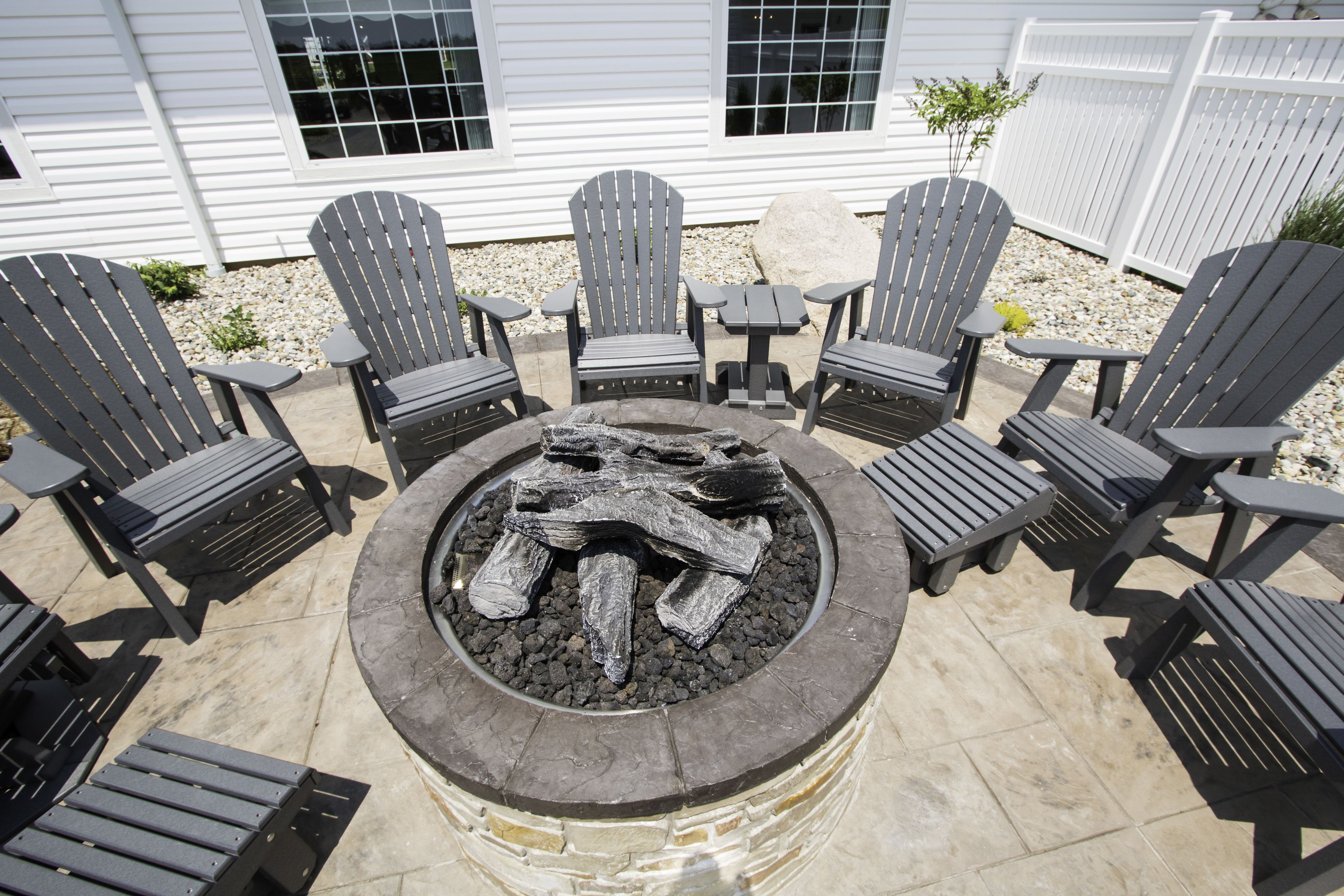 A patio with Adirondack chairs and a stone fire pit.