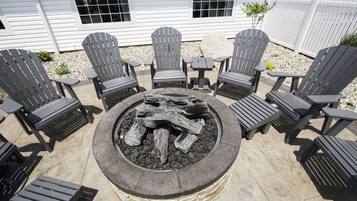 A patio with Adirondack chairs and a stone fire pit.