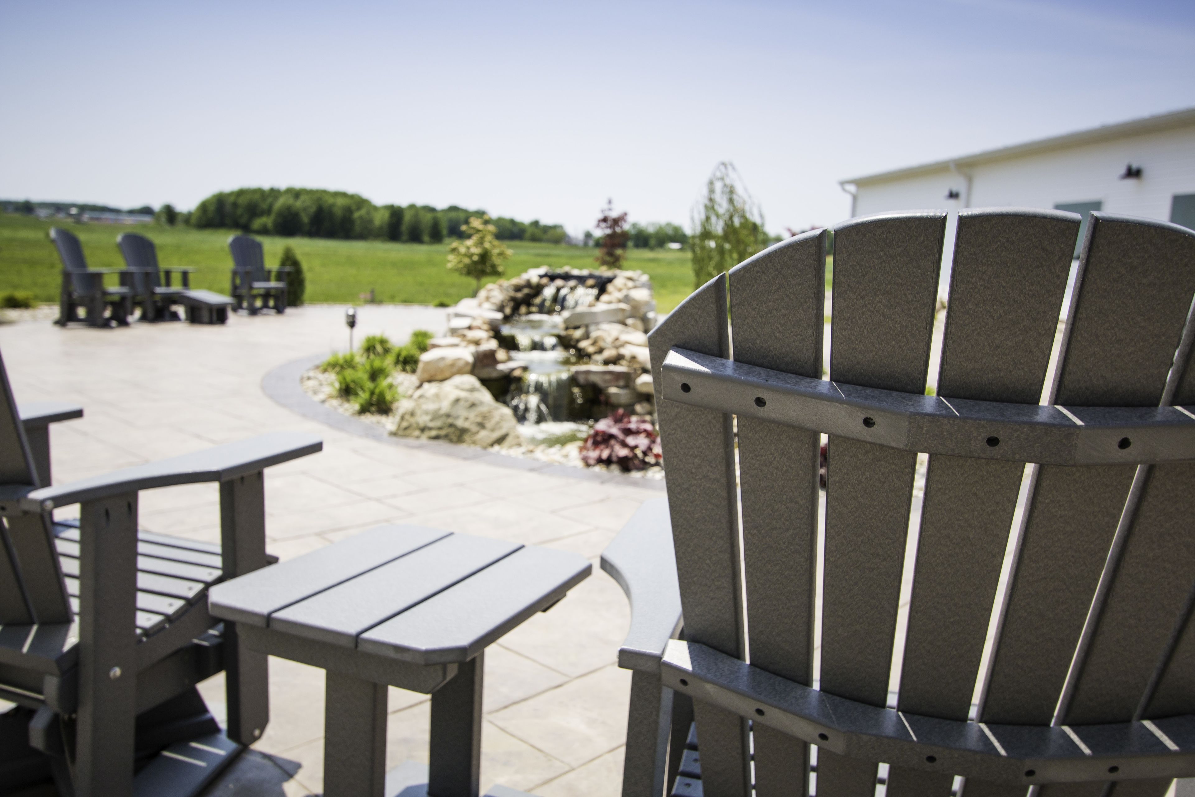 A patio area with Adirondack chairs and a stone feature.