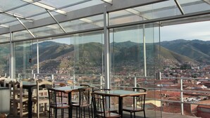 Un restaurante con techo de cristal que ofrece una vista panorámica de la ciudad y montañas.
