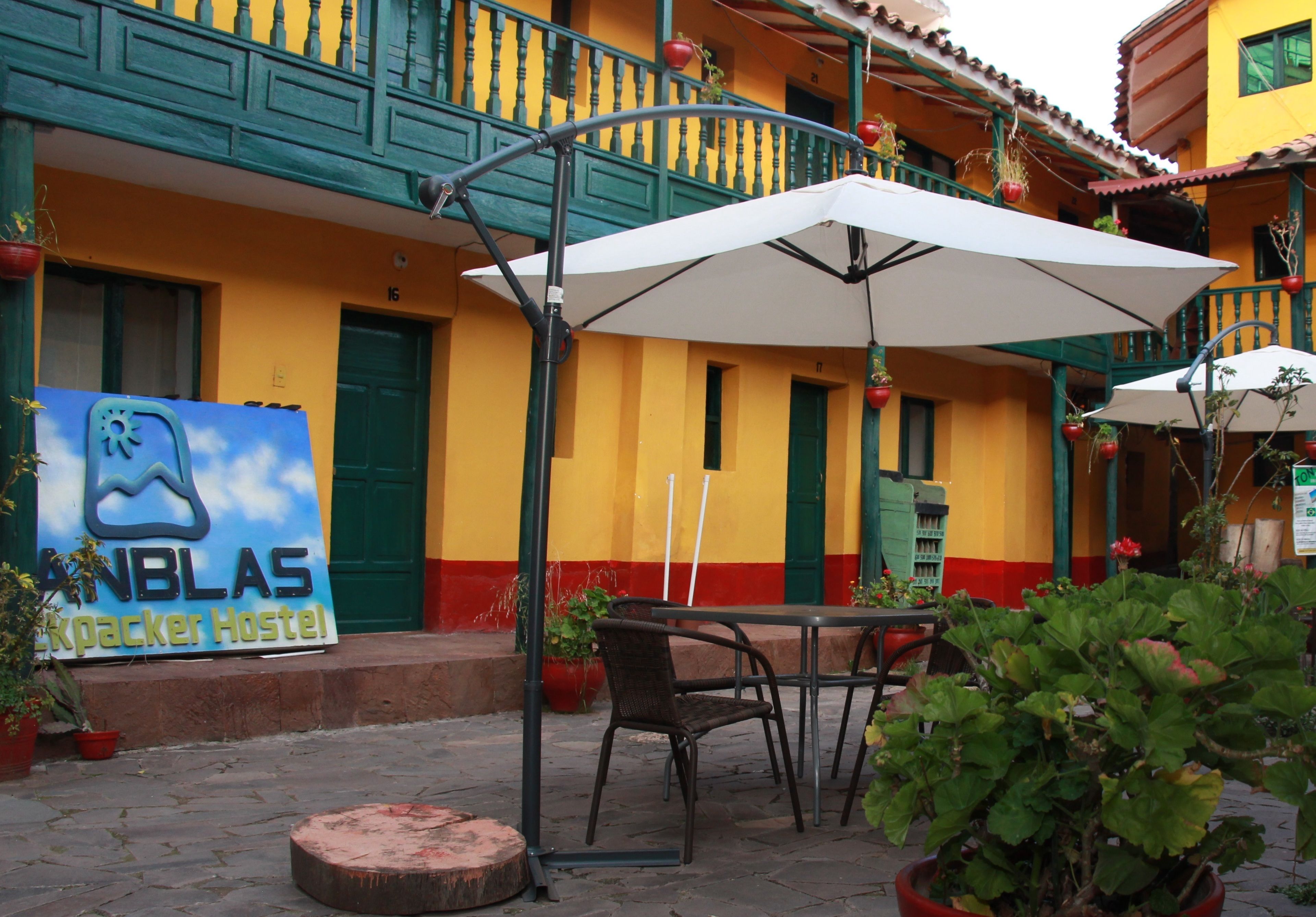 A hostel with outdoor seating, a signboard, and potted plants.