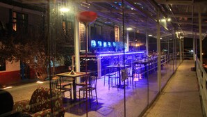 Un restaurante interior con paredes de vidrio, mesas y sillas dispuestas para comer.