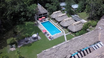 Una piscina al aire libre, sombrillas, sillones reclinables de piscina