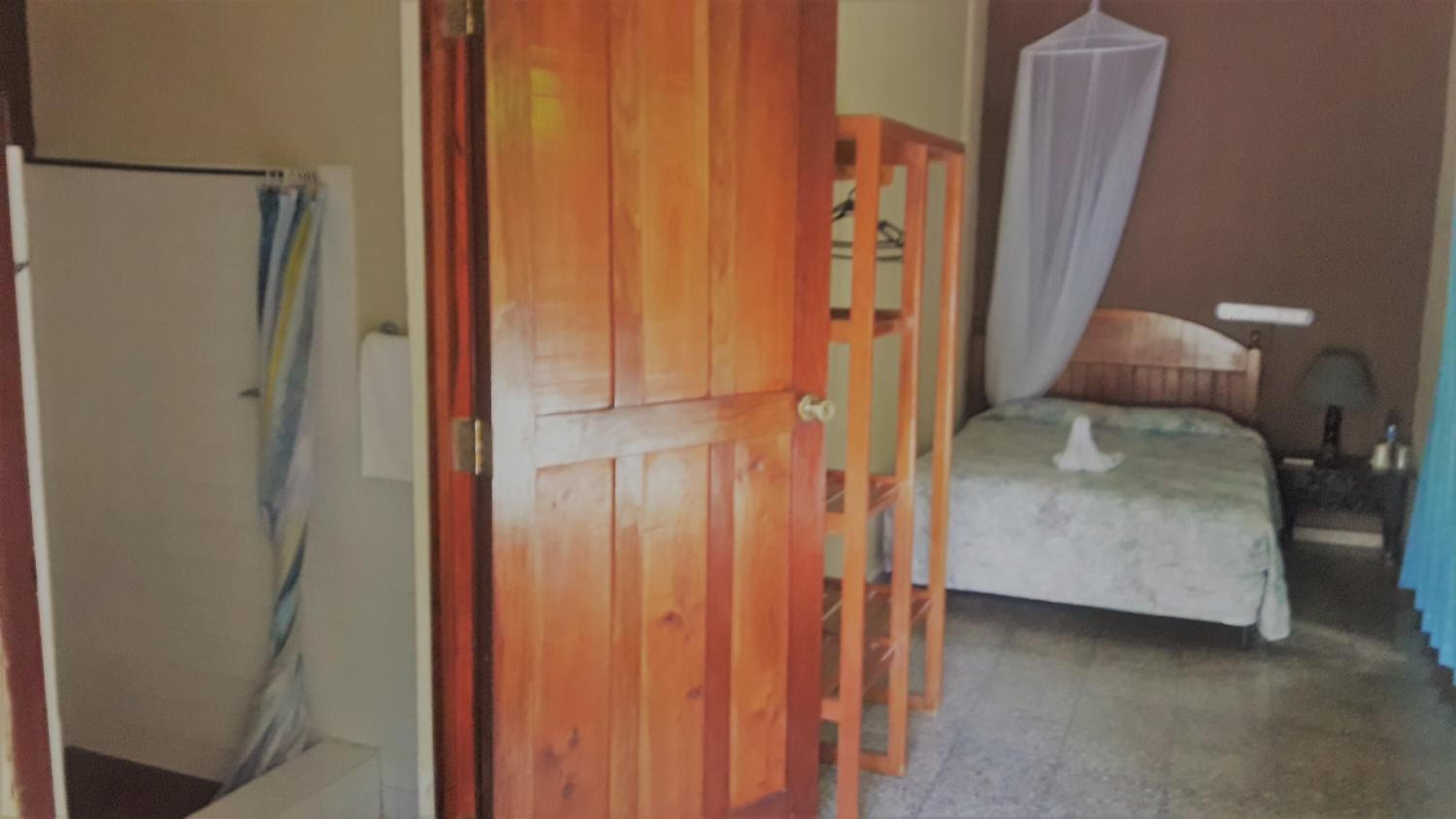 Une chambre à coucher avec un lit, une porte en bois, une table de chevet et une commode.